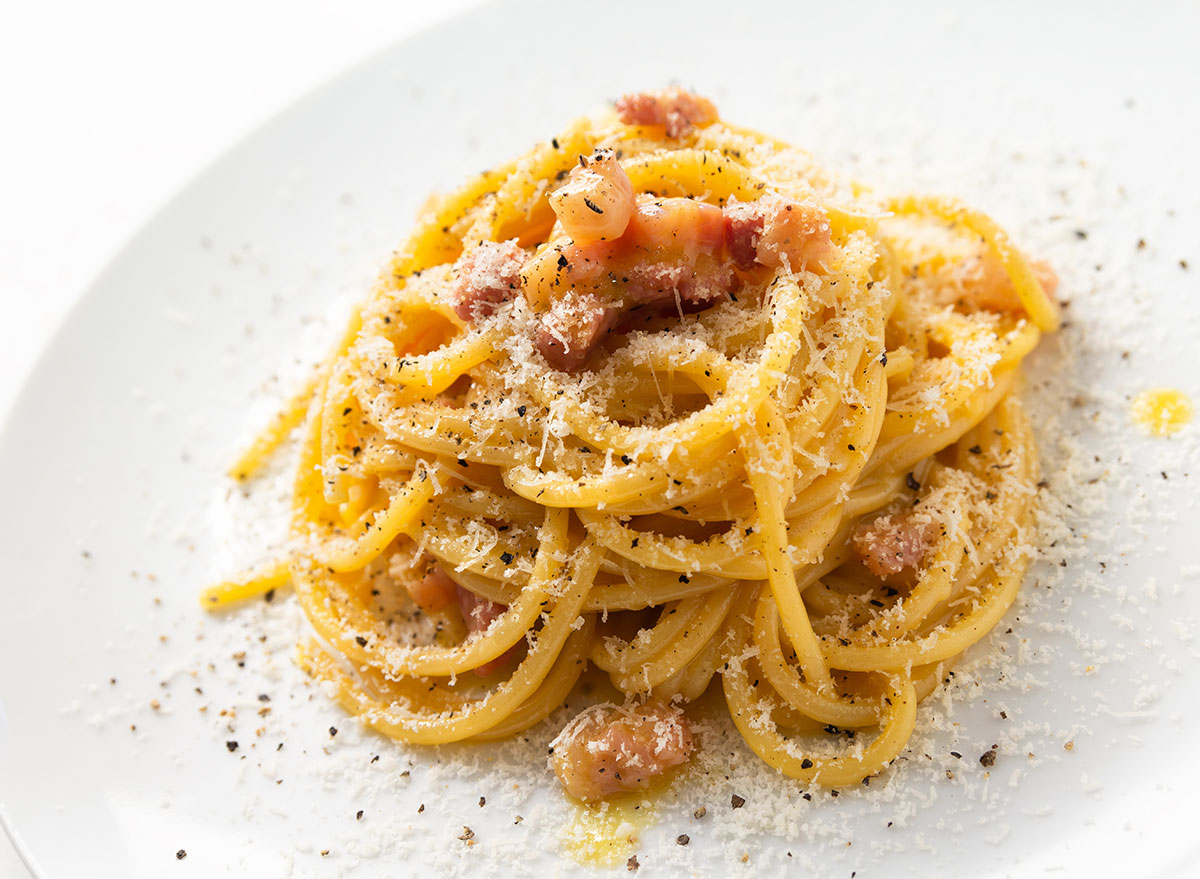 Sprinkled pecorino romano cheese on a bed of cheesy pasta