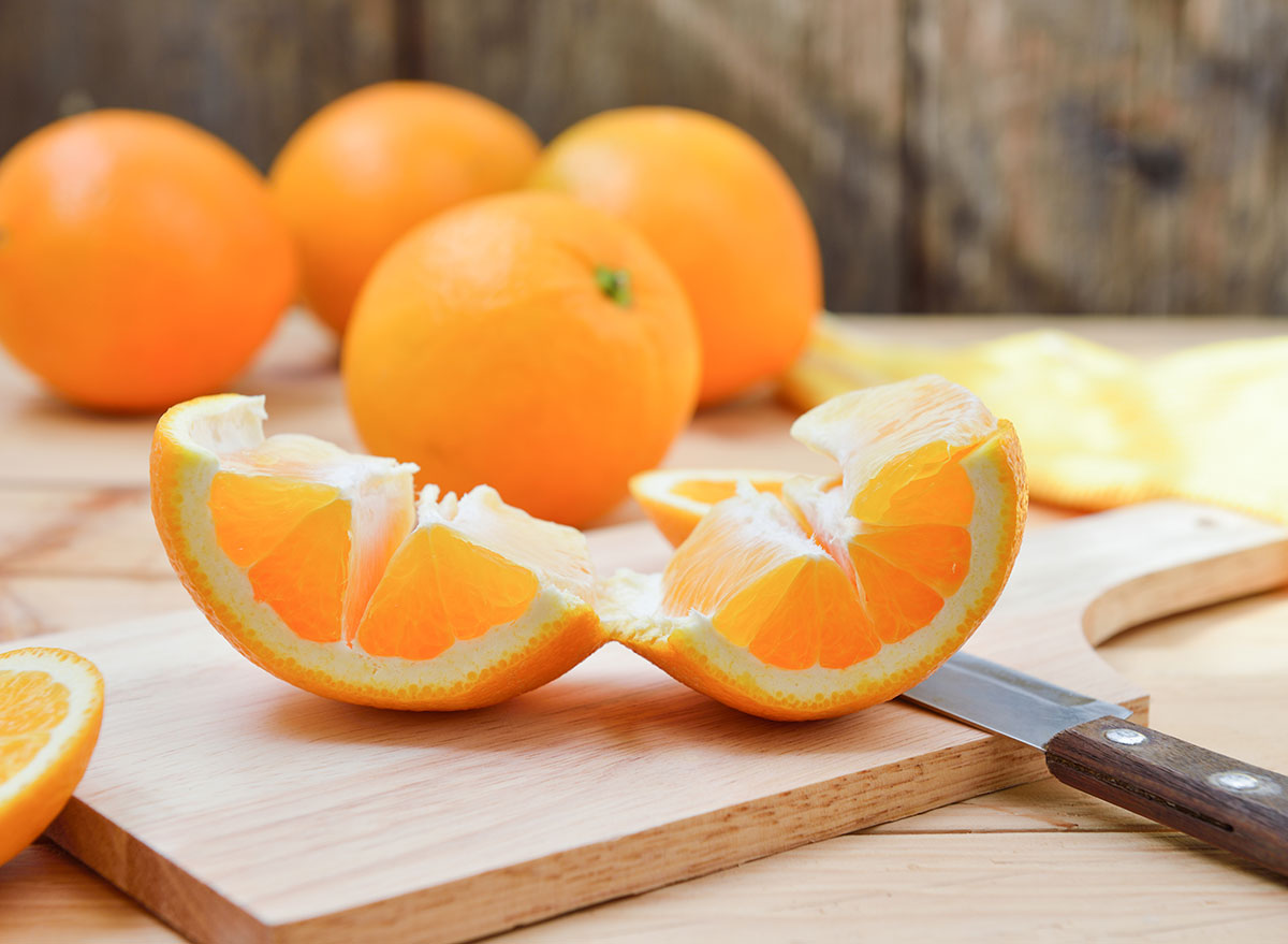 Peeling and unrolling an orange easily on a cutting board.