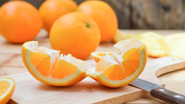 Peeling and unrolling an orange easily on a cutting board.