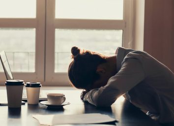 woman lying her head down on a desk