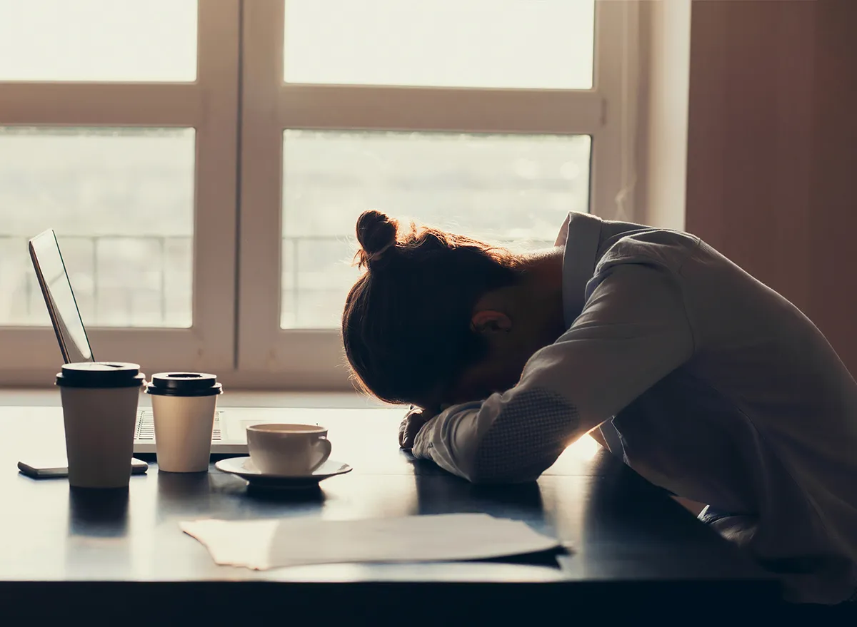 woman lying her head down on a desk