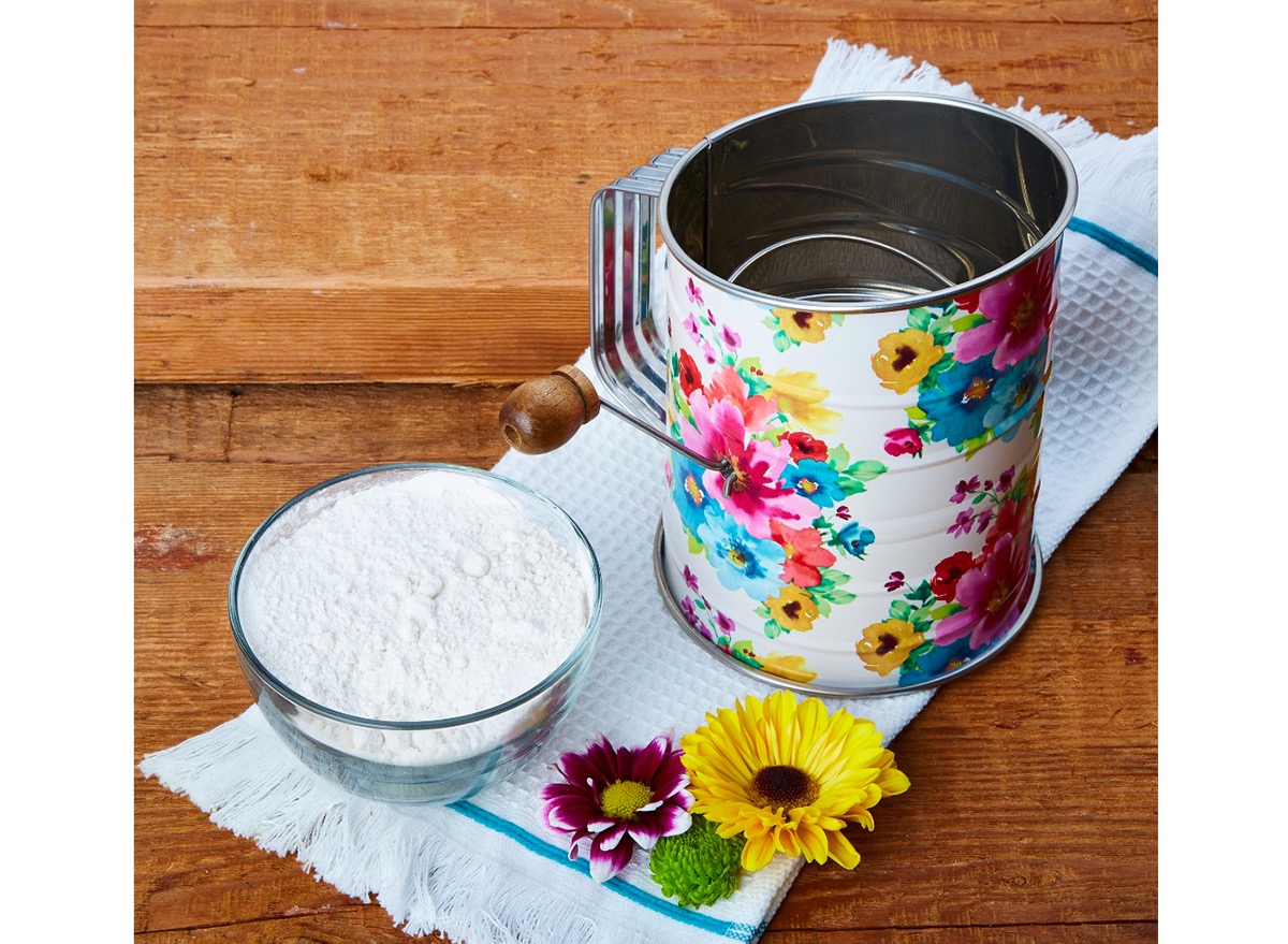 floral flour sifter on white tea towel with purple and yellow flowers