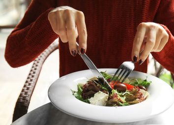 Woman eating a salad with vegetables and tofu.