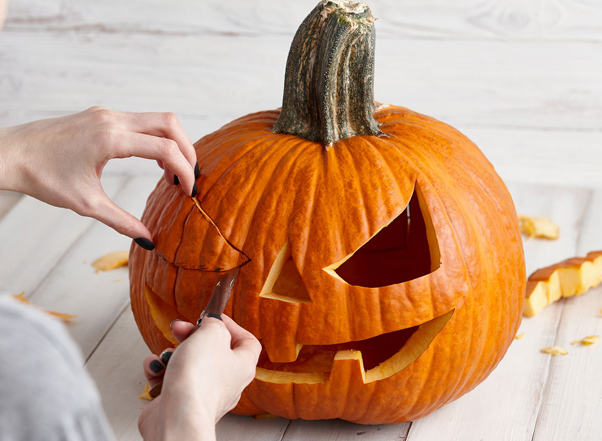 woman carving pumpkin jack-o-lantern