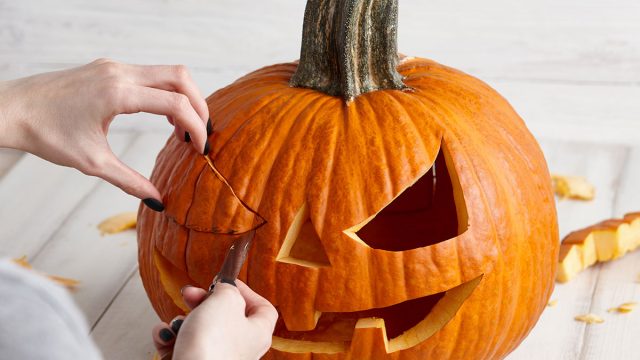 woman carving pumpkin jack-o-lantern