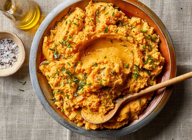 Pumpkin potato mash in a large bowl with chives, oil, and salt.