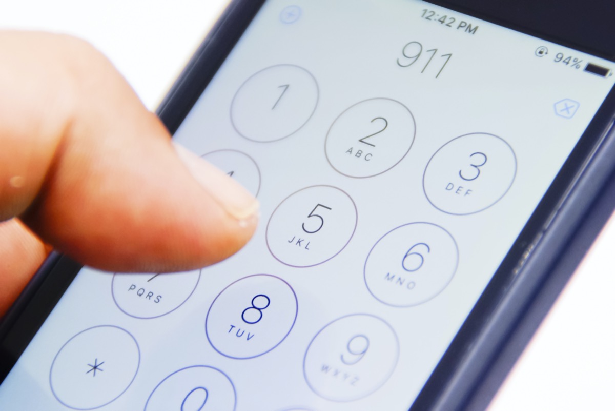 هاتف ذكي يحمل باليد مع رقم الطوارئ 911 على الشاشة
