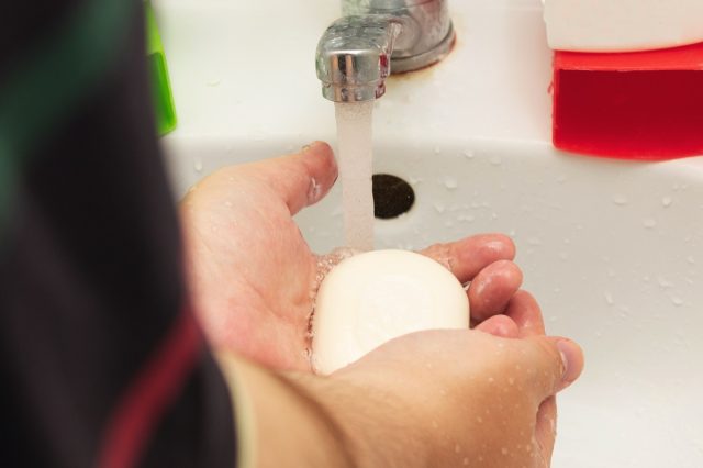 man washes his hands with soap in the sink