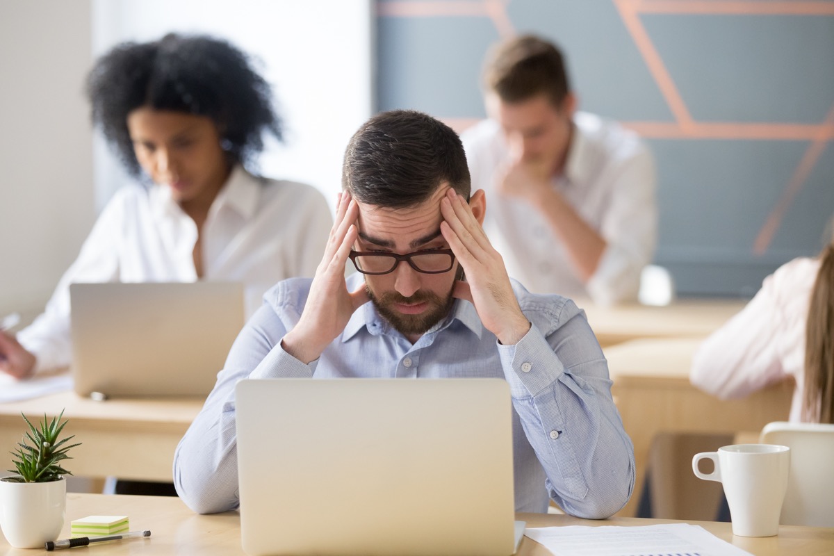 frustrated worried male employee reading news, tired exhausted office worker feeling headache at work
