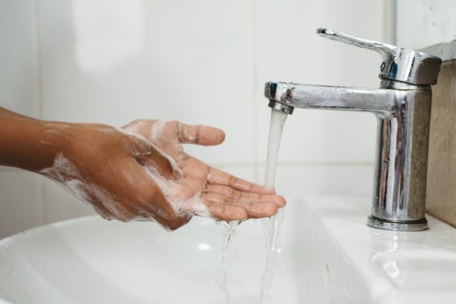 scrubbing soapy hand against washbasin