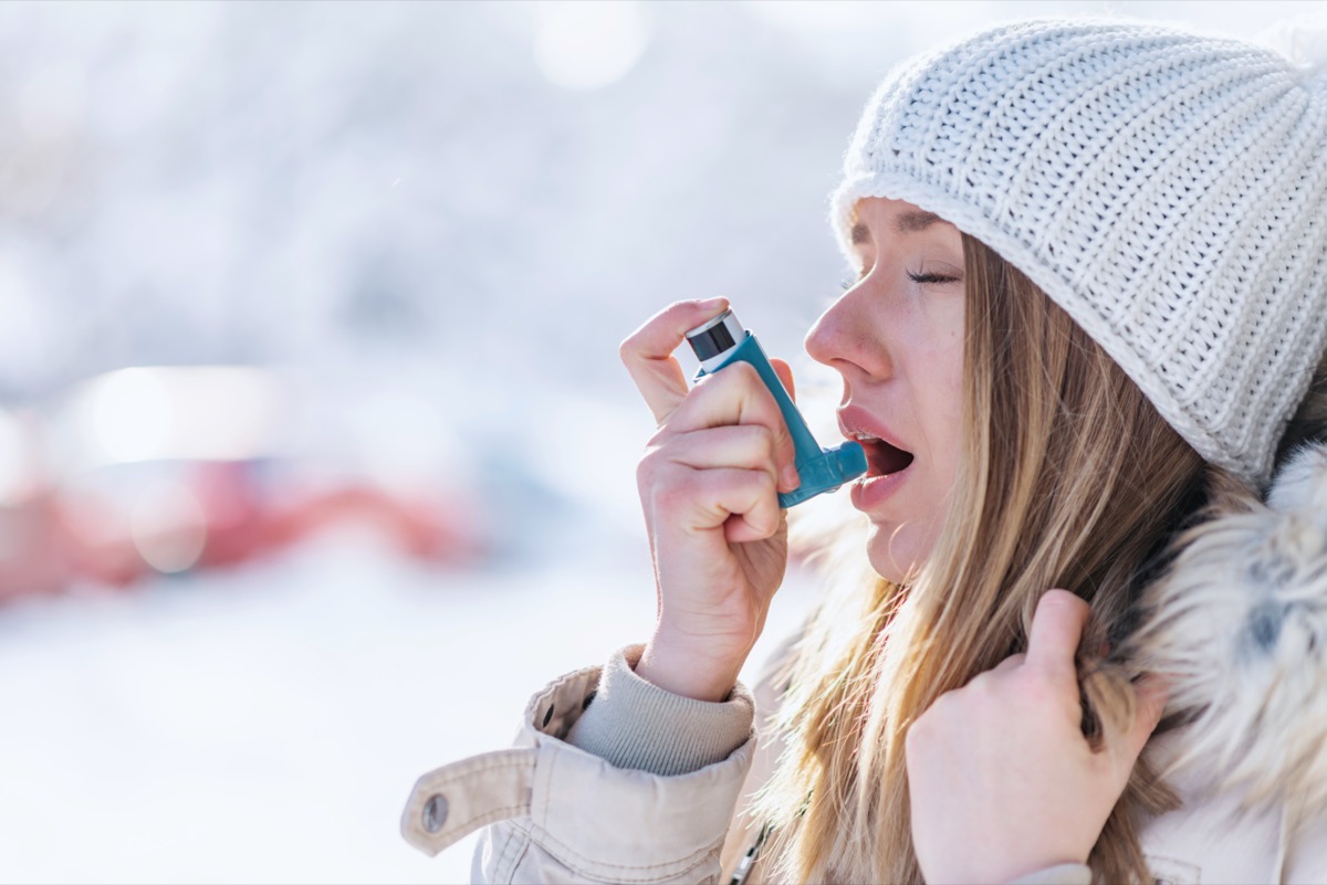 A woman using an asthma inhaler in a cold winter