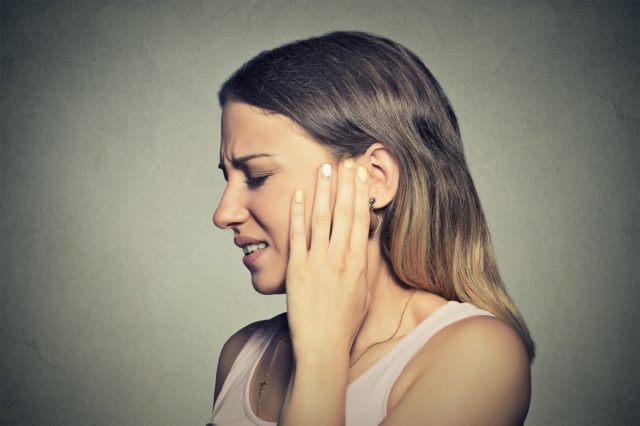 woman having ear pain touching her painful head
