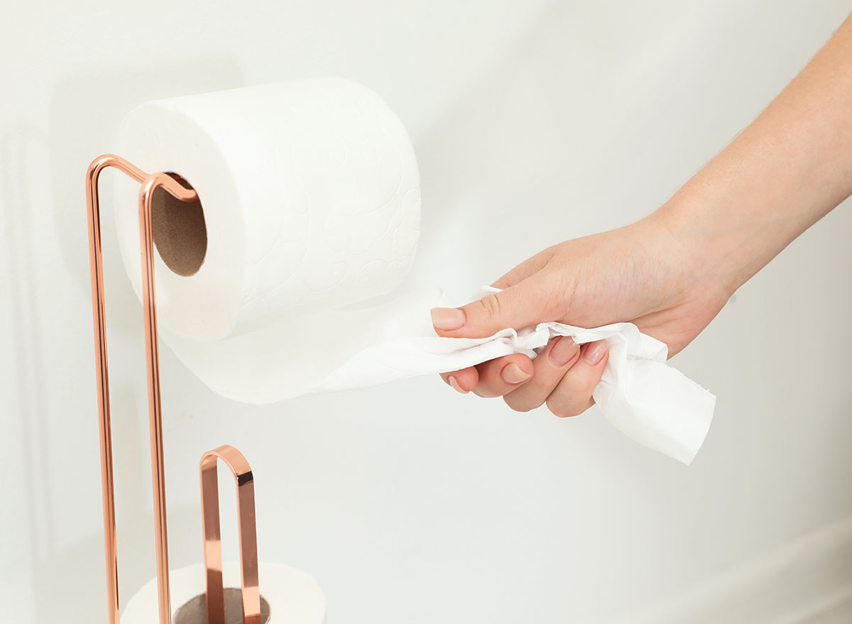 woman grabbing toilet paper from the roll