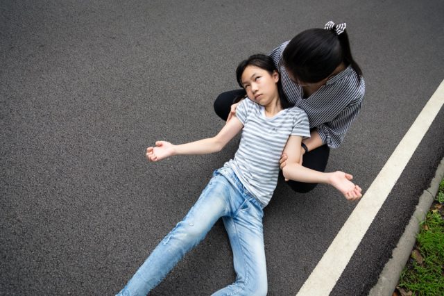 Sick little child girl with epileptic seizures outdoor,daughter suffering from illness with epilepsy during seizure attack
