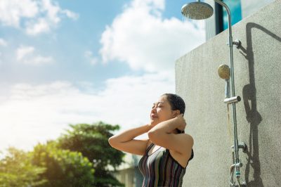 Female side view enjoying shower before swim