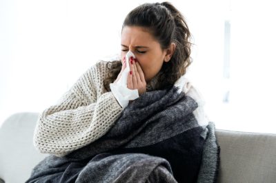 illness young woman sneezing in a tissue