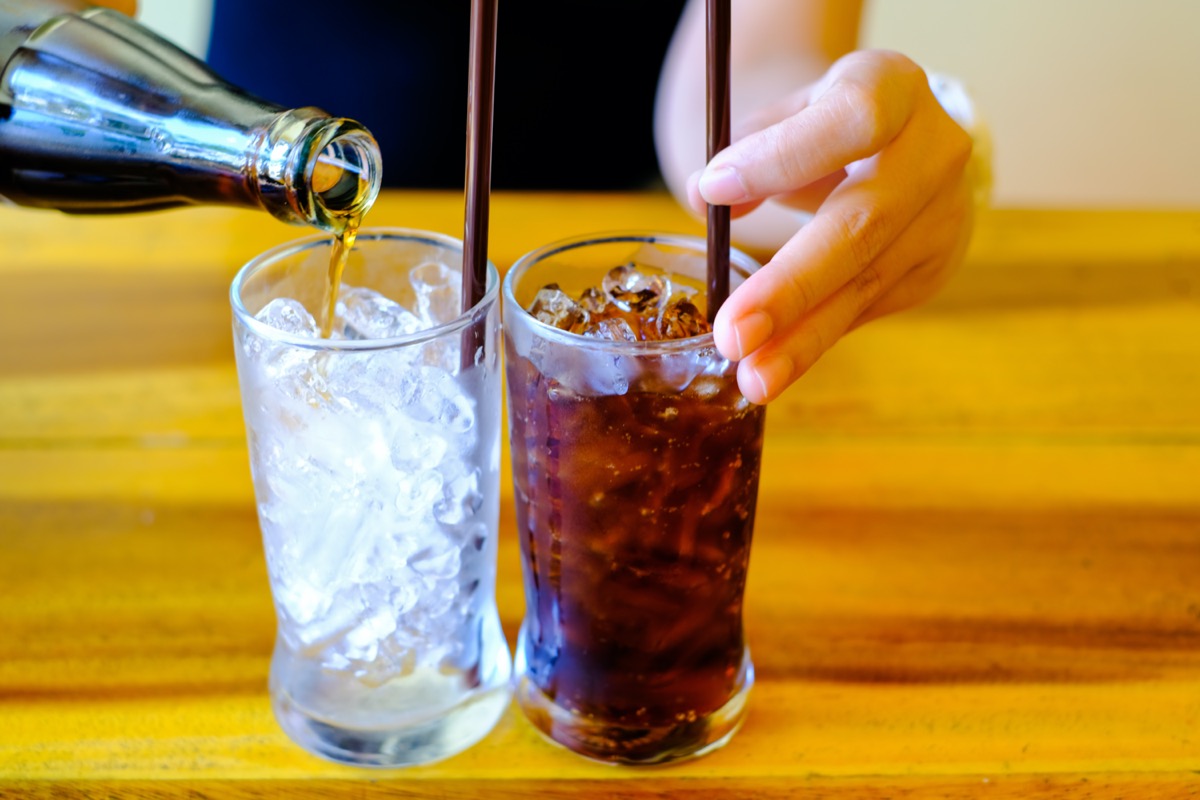 Woman hand giving one glass of Soft drinks with ice. and one Glass with ice in glass ready to refresh you