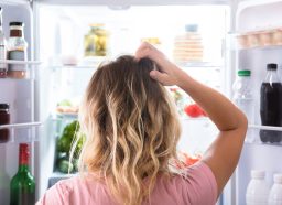woman standing at fridge hungry and confused