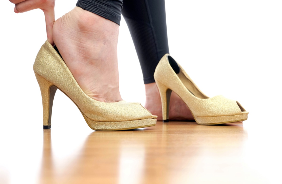 Women are wearing gold high heels. Her hand catches high heels.