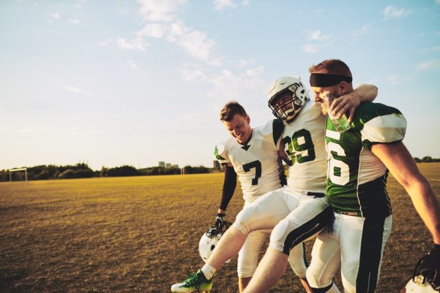 American football players carrying an injured teammate off the field during a practice session