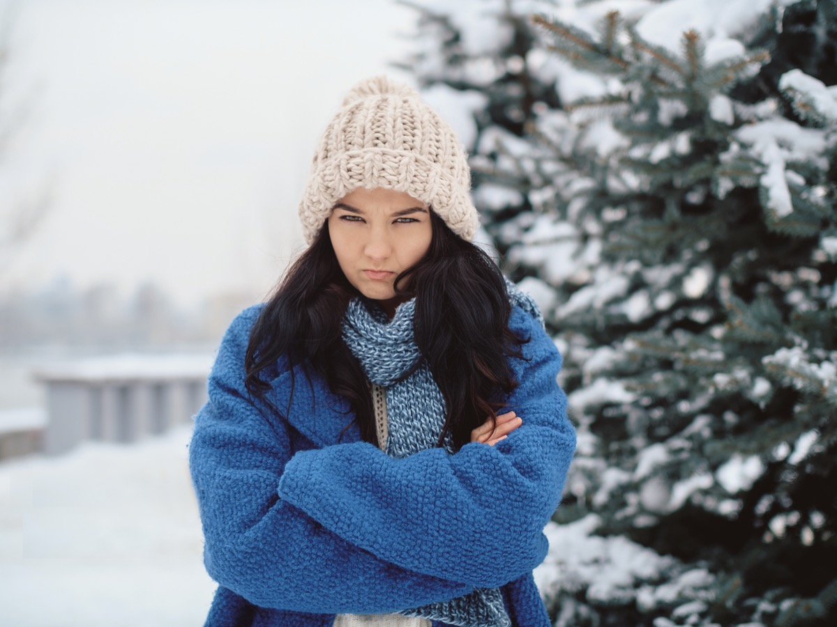Unhappy winter woman in beautiful warm coat hat and scarf outdoors