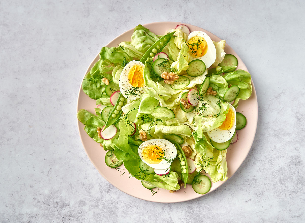 breakfast salad with eggs on pink plate and marble background