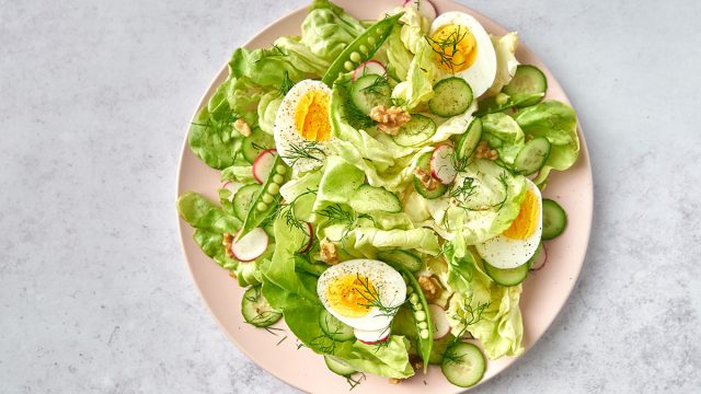 breakfast salad with eggs on pink plate and marble background