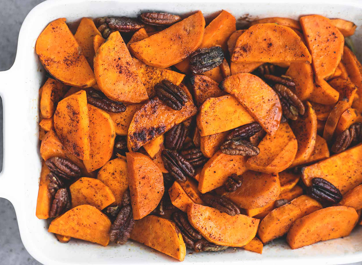 baking dish filled with sliced candied sweet potatoes and pecans