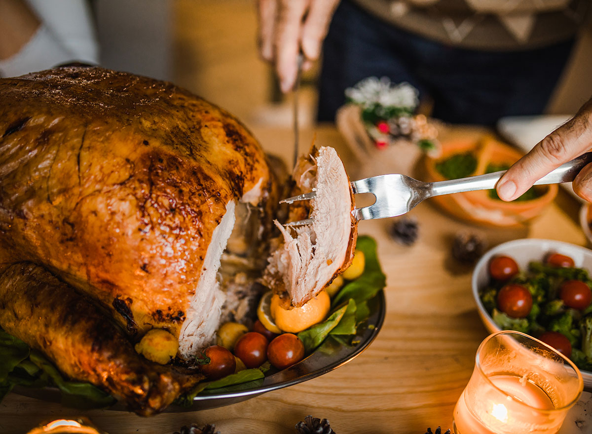 Close up of unrecognizable man carving roasted Thanksgiving turkey.