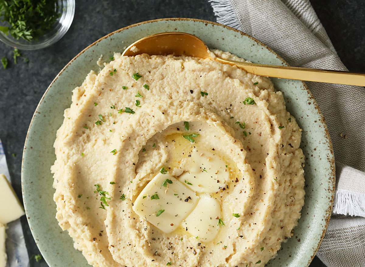 bowl of cauliflower mashed potatoes with pat of butter and seasoning