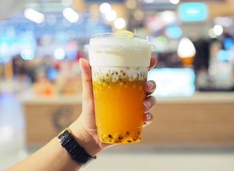hand holding chinese iced tea with boba and cream cheese foam