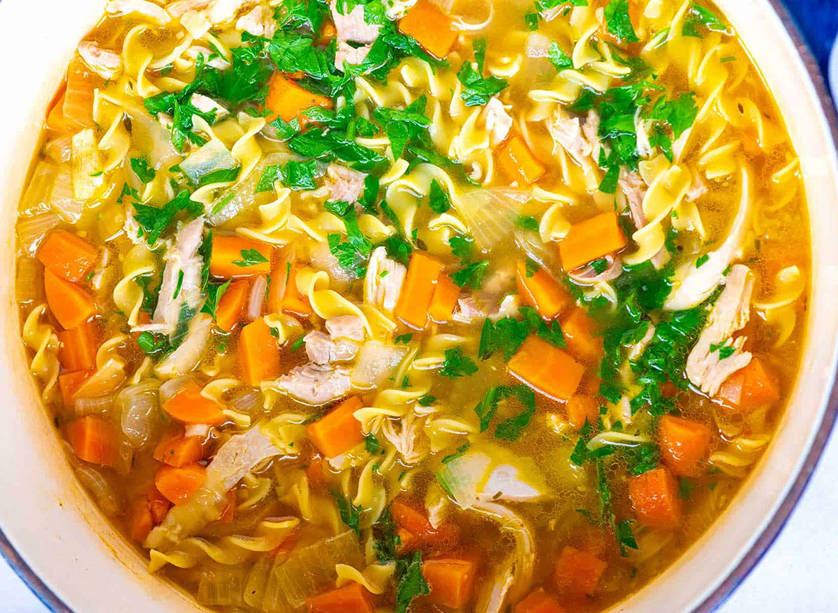 bowl of chicken noodle soup with parsley and carrots