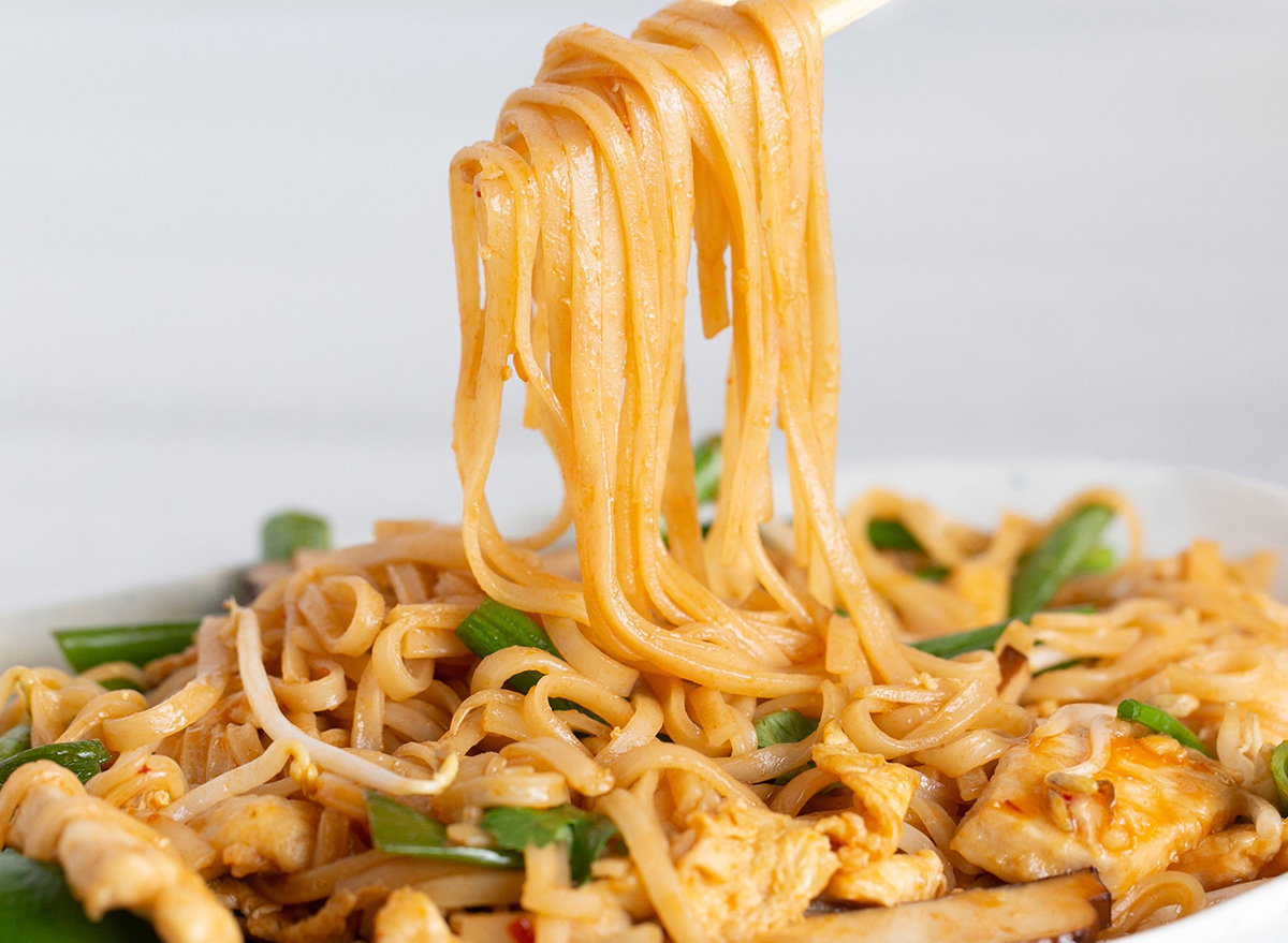 lifting noodles from a bowl of chicken pad thai