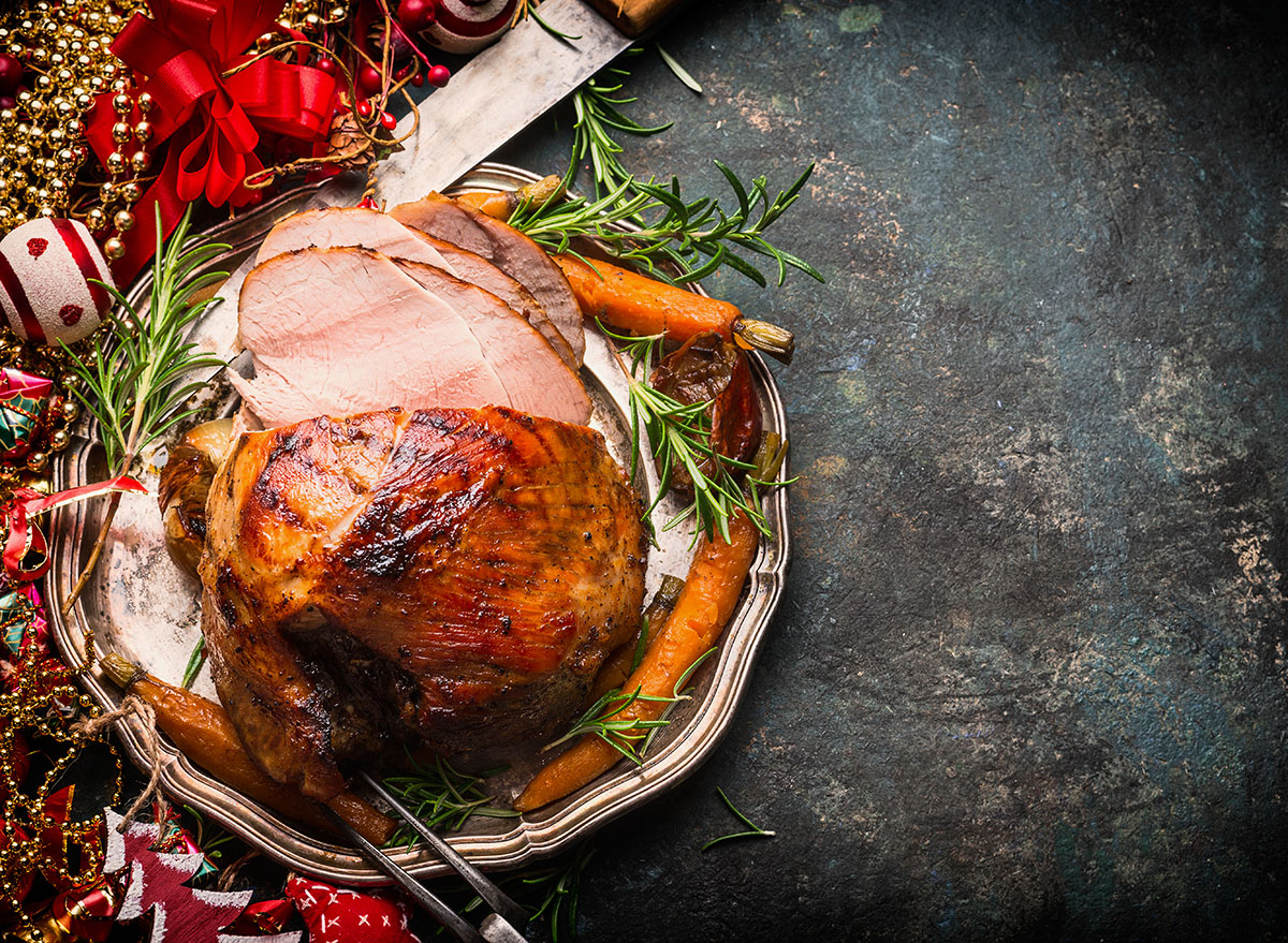 christmas ham on silver plate with roasted carrots and rosemary