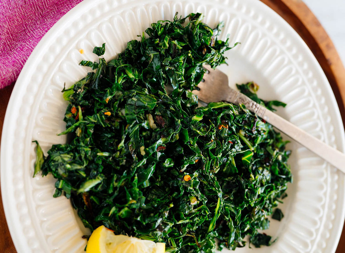 plate of cooked collard greens with lemon wedge