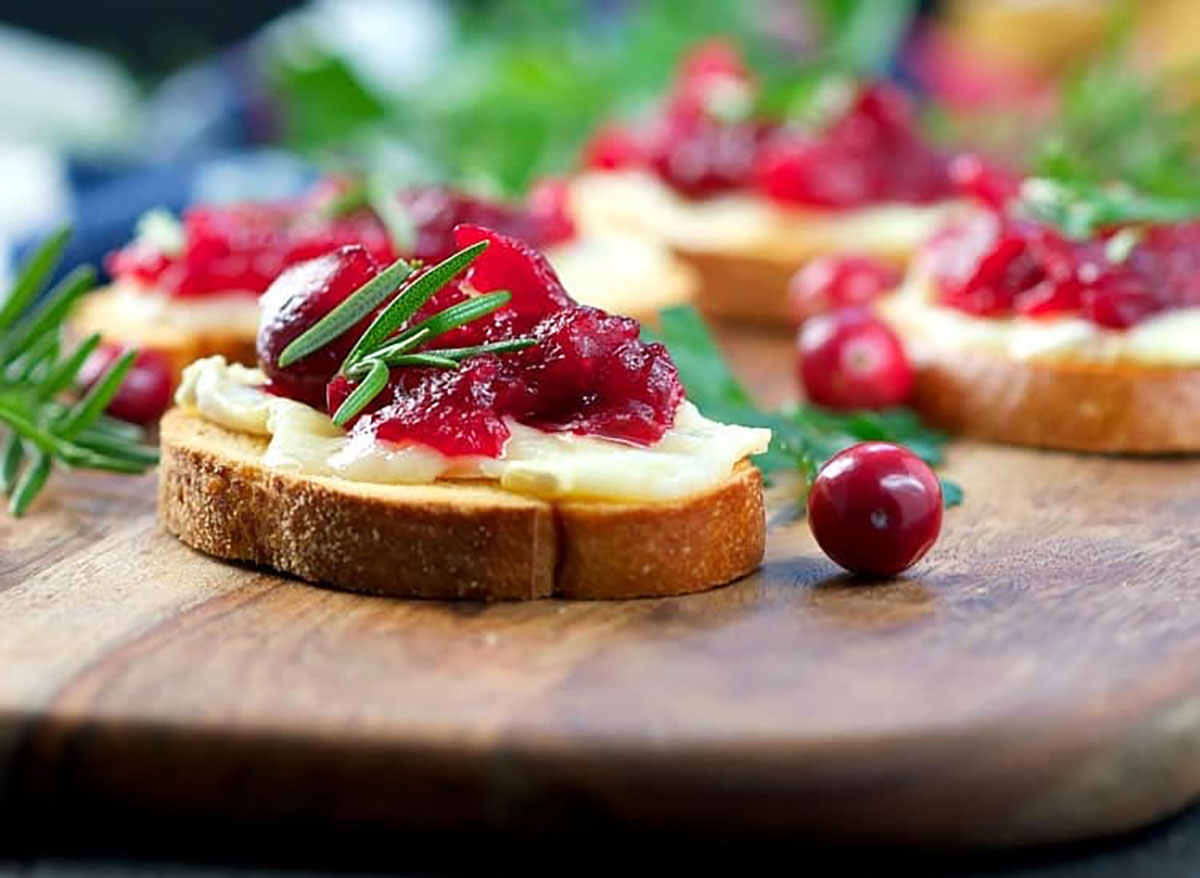 slice of toast with brie cheese and cranberry sauce on wood board