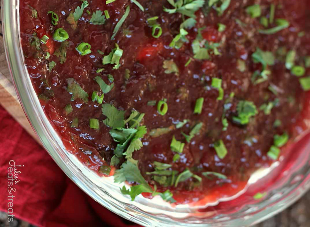 cream cheese cranberry dip in glass jar garnished with cilantro