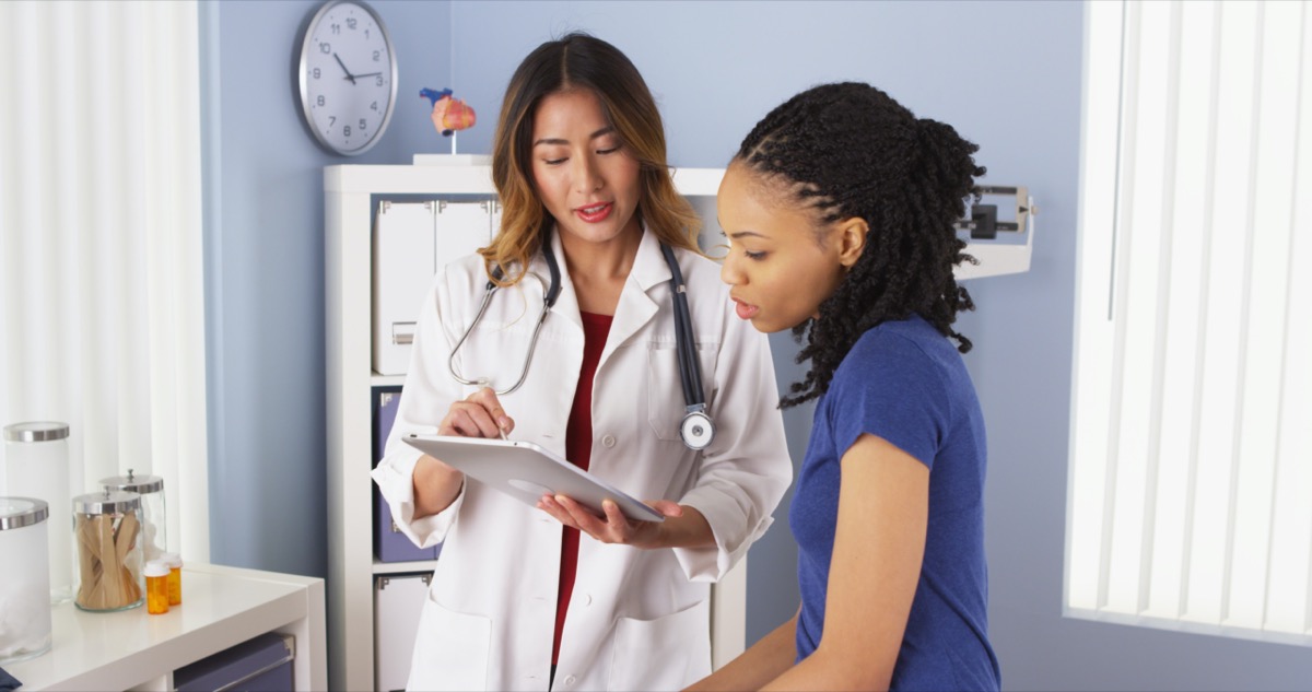 patient explaining issues to Asian doctor using tablet