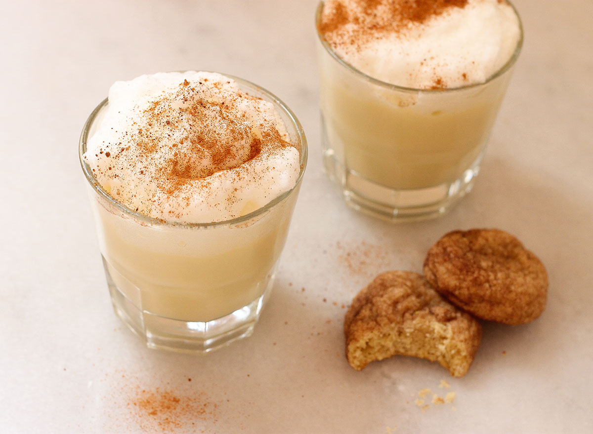 sprinkled nutmeg and cinnamon on two cups of eggnog next to cookies