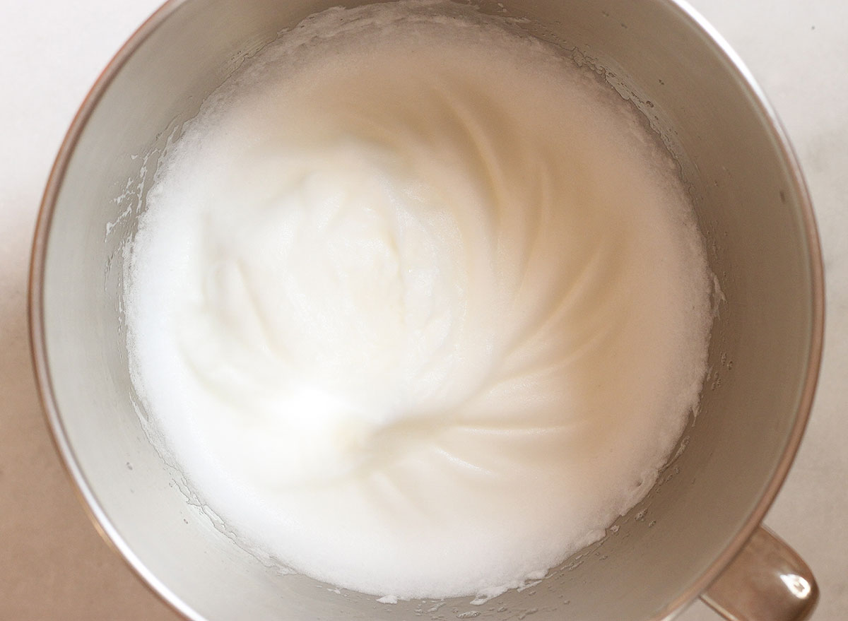 whisking egg whites in a large stainless steel bowl