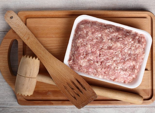 ground chicken in package on cutting board with wooden cooking tools