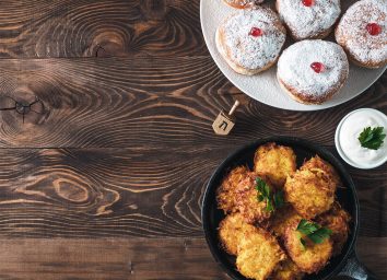 jelly donuts and latkes with dreidel on table