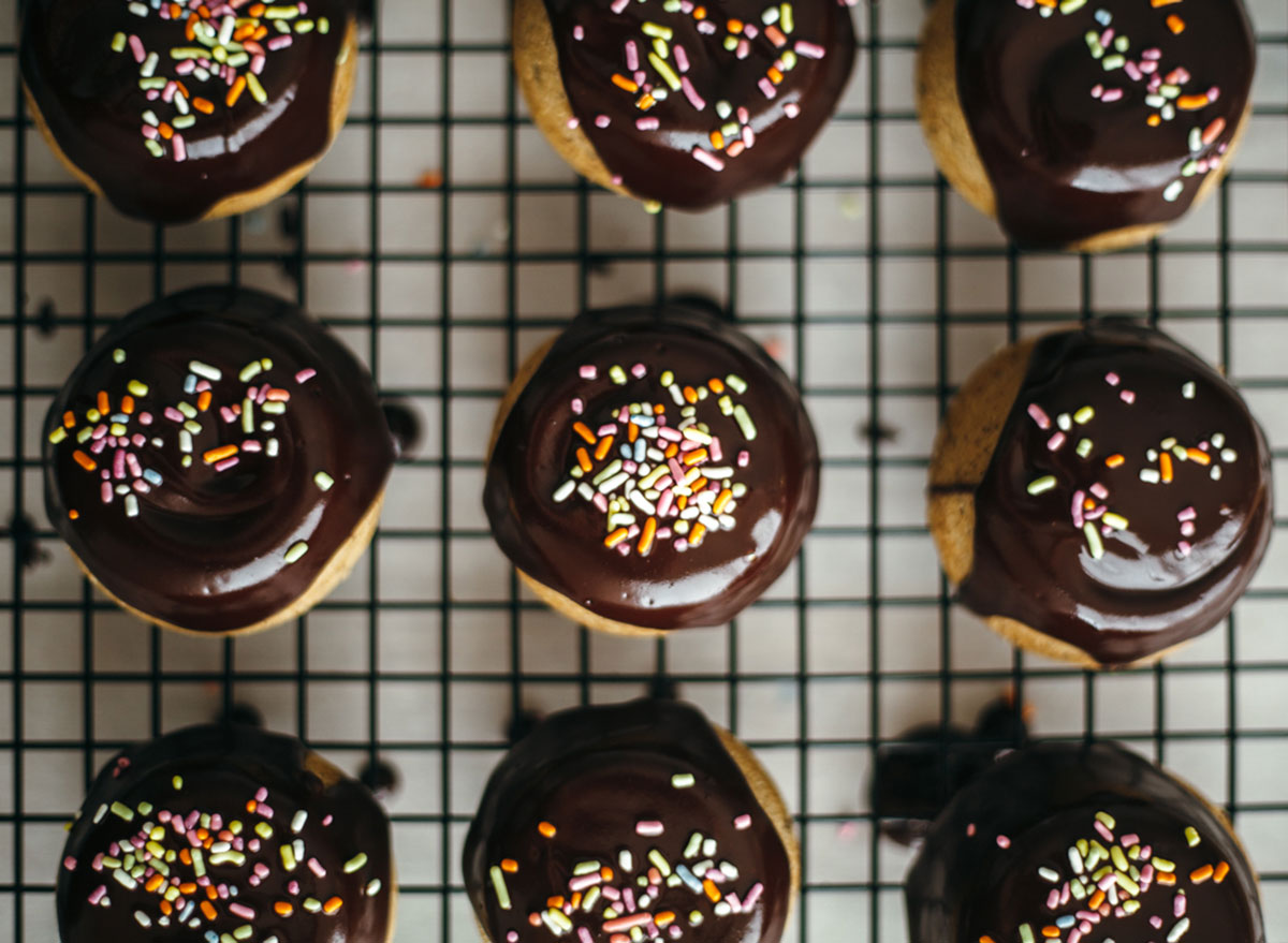 hazelnut mini cakes on baking tray with sprinkles and fudge topping