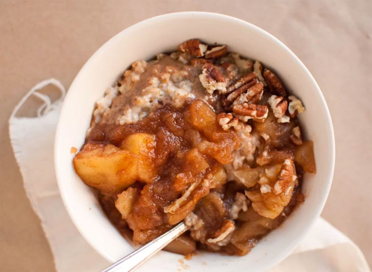 bowl of oatmeal topped with homemade cinnamon applesauce and pecans