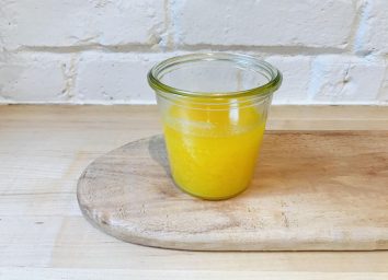 homemade ghee in glass on wooden surface