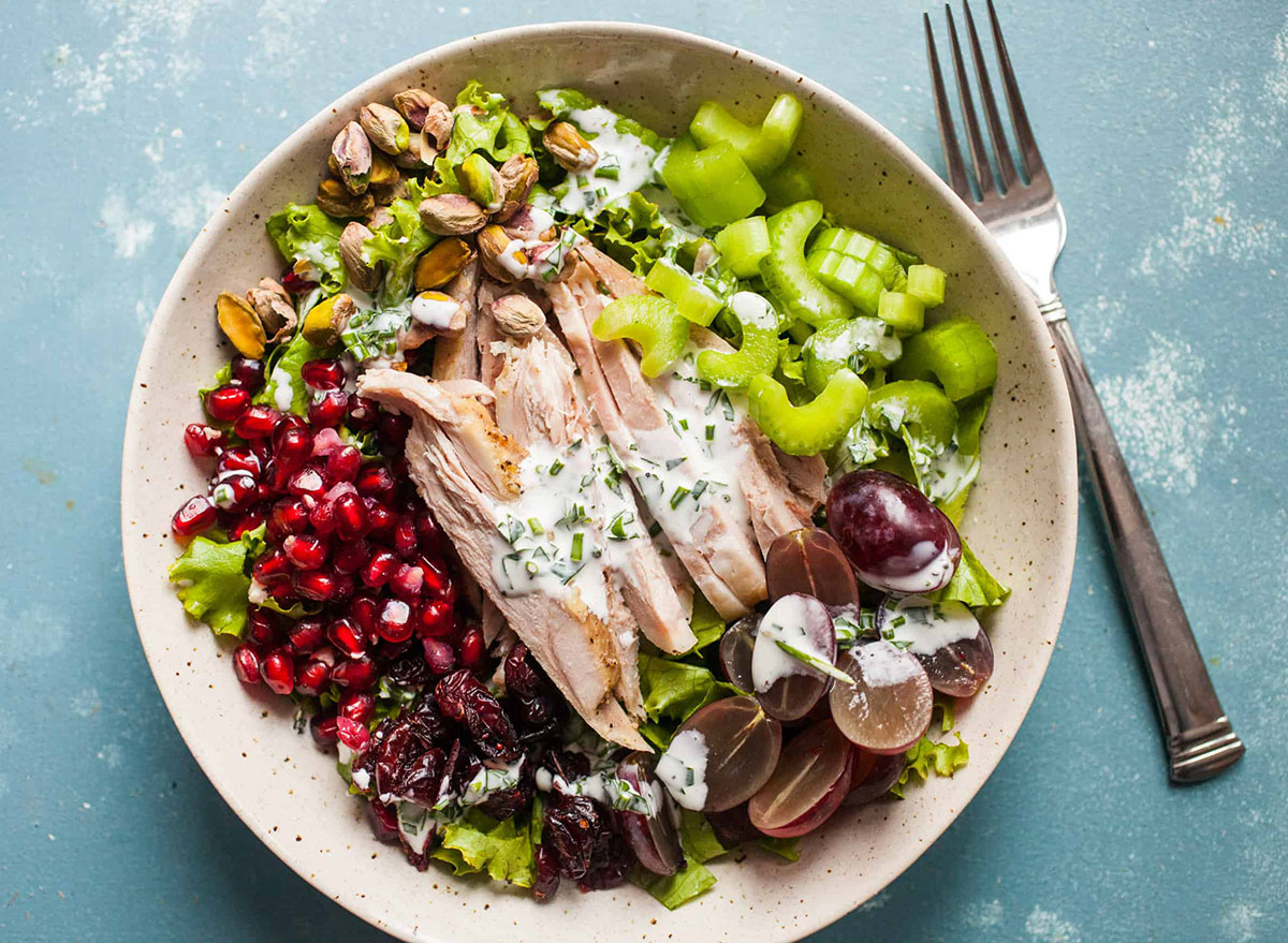 turkey waldorf salad with pomegranate seeds grapes celery lettuce in white bowl
