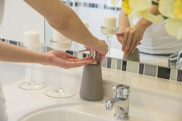 Female hands using wash hand sanitizer gel pump dispenser