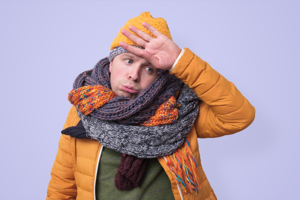 man in several hats and scarfs in stressed on colored background