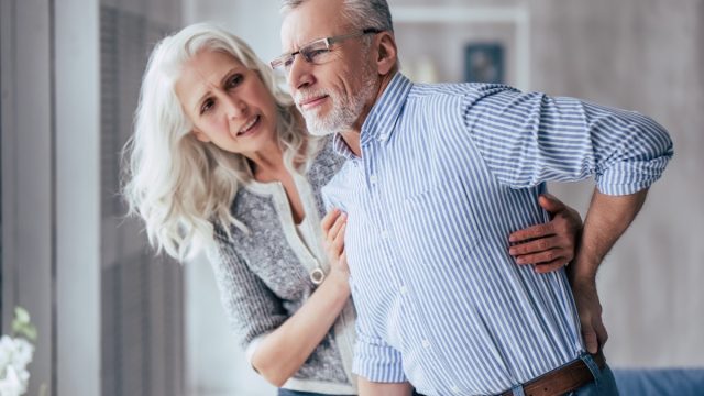man is having back pain and his attractive old woman supports him