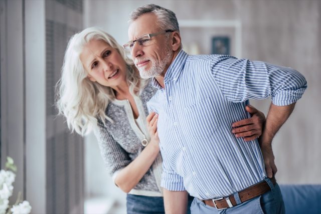 man is having back pain and his attractive old woman supports him
